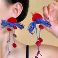 Detail view of avant-garde red resin disk earrings with blue woven knots and long tassels - Red and Blue Woven Knot Sequin Tassel Avant-Garde Earrings