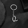 Polished stainless steel keychain with artistic letter Q pendant on black rock base - Letter Q