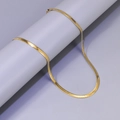Elegant gold-plated flat snake bone chain necklace displayed on a minimalist pedestal - L38-Flat Snake Chain / Gold