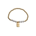 Detailed close-up of gold beaded bracelet with white pearls and letter W charm - Letter W