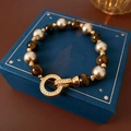 Detalle macro de pulsera vintage con piedras ojo de tigre y cierre de circonita - Café (Chapado en Oro Real)
