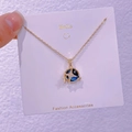 Dettaglio di una collana con ciondolo stella e pianeta finitura oro su carta da esposizione - Pentacolo di Diamanti (XK0017)