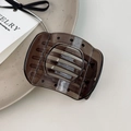 Close-up of a tortoiseshell hair claw clip with a glossy finish on a ceramic plate - Small Gray