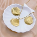 Elegante gouden schelpketting en oorbellen set op een witte schelpvormige schaal - Schelp 3-delige Set / Goud