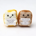 Macro detail of two crochet toast plushies with emotional support cards on white backdrop - Bread Couple