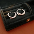 Detailed close-up of silver zircon twisted hoop earrings resting in a black velvet jewelry box - Silver