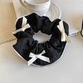 Détail d'un chouchou noir texturé avec trois nœuds blancs sur un bureau au style épuré - Chouchou Nœud Blanc Cassé