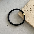 Macro shot of black high-elastic hair tie with twill texture and gold metal connector - Black