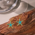 Boucles d'oreilles étoile de mer dorées et émail bleu brillant sur fond en bois naturel - Boucles d'Oreilles Pendantes Étoile de Mer Émail Bleu (G279) / Or