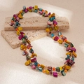Detalle de cuentas de concha irregulares y cristales en un collar de playa boho - Morado