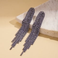 Detailed close-up of purple tassel earrings with sparkling rhinestones on white stone - Purple - Style 1