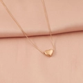 Detalle de colgante de corazón en oro rosa con cadena de serpiente sobre tela rosada - Oro rosa