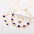 Detail shot of golden heart jewelry set with blue crystal inlays on a white tray - 4Pcs Set (Necklace+Bracelet+Earrings+Ring) / Blue