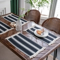 Set of four black woven placemats with ethnic patterns and white tassels on a table - Deep Forest White Tree