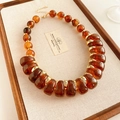 Détail du collier de perles d'ambre vintage avec séparateurs dorés et chaîne réglable - Marron
