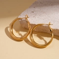 Détail de boucles d'oreilles créoles plaquées or 18 carats sur un socle en pierre - Petit (3cm) / Doré