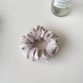Détail d'un chouchou en satin rose champagne montrant d'élégants plis et un doux éclat soyeux - Violet Taro