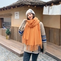 Vibrant orange cashmere-feel scarf with fringe tassels worn by a model in a retro setting - Bright yellow