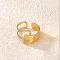 Close-up of golden wide band ring featuring hollow heart pattern on beige surface - Heart