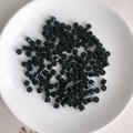 Macro view of polished black cylindrical acrylic spacer beads scattered on a white tray - 7# Black