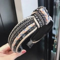 Detail of hand-held knotted velvet headband with sparkling sequins and woven rope trim - Black