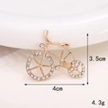 Detalle de dimensiones y peso de un broche de bicicleta dorado con piedras brillantes - Bicicleta de Diamantes de Imitación Dorada
