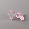 Macro detail of two translucent pink cross beads with vertical holes for DIY jewelry - Pink