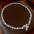 Detail of a pearl necklace with a zircon butterfly clasp on dark leather and silk - White (6-8mm)