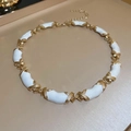 Dettaglio di maglie a X dorate con segmenti in smalto bianco su una collana vintage - Oro-Bianco