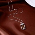 Macro detail of silver box chain necklace with rectangle gemstone pendant on silk - Silver-Coffee