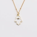 Macro view of gold Hamsa Hand necklace pendant with white enamel and eye detail - White