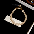 Vista dettagliata di un bracciale a maglia ritorta dorata in una confezione regalo - Intrecciato / Oro / Bracciale