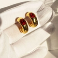 Vintage gold plated C-shaped hoop earrings with red oval ruby zircons shown in sunlight - Red