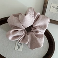 Gros plan d'un chouchou rose brodé avec motifs nœuds et étiquette en tissu - Broderie Nœud / Rose
