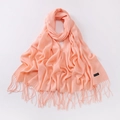 Detailed macro view of coral pink scarf with tassels and Classic Scarf woven label - Pale Green