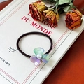 Elegant black hair tie with gradient purple flower and pearl on a vintage book - Iridescent Purple Green