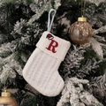 Weiße gestrickte Weihnachtssocke mit rotem Buchstaben R am verschneiten Tannenbaumzweig - Bestickte kleine Strickstrumpf Weiß R
