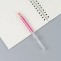Roze markeerstift in de vorm van een spuit met vloeibare inkt op een ruitjesnotitieboek - Roze