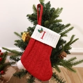 Red knitted Christmas stocking with letter I embroidery hanging on a festive tree branch - Letter I