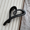 Detail shot of a matte black heart-shaped hair claw clip on a minimalist jewelry tray - Matte Black