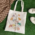 White canvas tote bag with watercolor ginkgo leaf print displayed on green grass - Ginkgo Leaf Print (STD344-D)