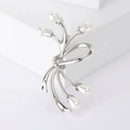 Dettaglio di spilla a fiocco argento con perle bianche e strass su base geometrica - Argento