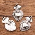 Three vintage silver sacred heart charms with flame details on a natural wood background - 27B2-8 Beaded Sacred Heart