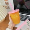 Pink lid straw cup with clear body and orange drink in a desk aesthetic setting - 470ML / Small Drink