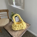 Handmade yellow woven cotton handbag resting on a vintage wooden table in a home setting - Yellow