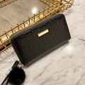 Long black faux crocodile skin zipper wallet featuring a golden metal accent and pompom charm - Black