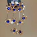 Dettaglio di orecchini lunghi con nappe a fiori dorati e perline blu eleganti - Blu