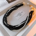 Close-up of multilayer beaded necklace with black beads, white pearls and gold clasp - Necklace-Black