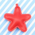 Red leather star pendant keychain with detailed stitching on blue striped background - Red