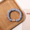 Close-up of a grey polka dot fabric scrunchie with a nude rectangular buckle on wood - Satin Polka Dot Mist Blue